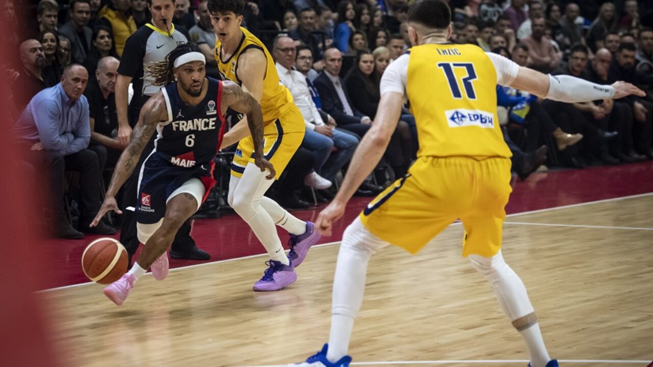 Baloncestista driblando con el balón, rodeado de otros jugadores en un partido.