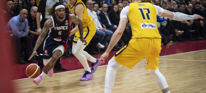 Baloncestista driblando con el balón, rodeado de otros jugadores en un partido.