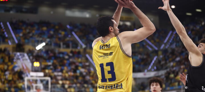 Jugador del Dreamland Gran Canaria lanzando el balón durante un partido, con público de fondo.