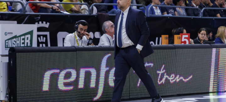 Entrenador caminando por la cancha durante un partido, observando el juego.