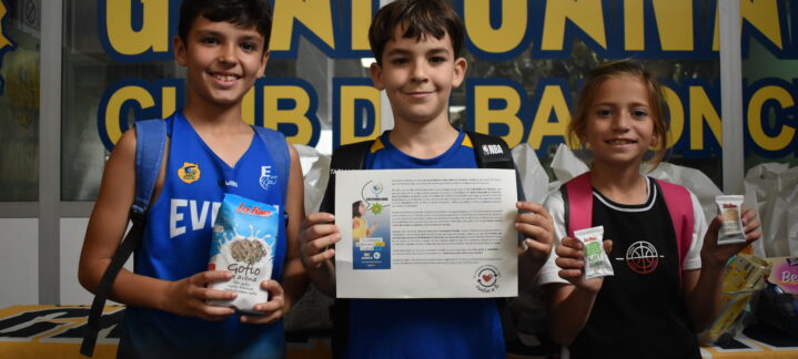 Niños sosteniendo productos locales y un documento en el X Clinic del Club Baloncesto Gran Canaria.