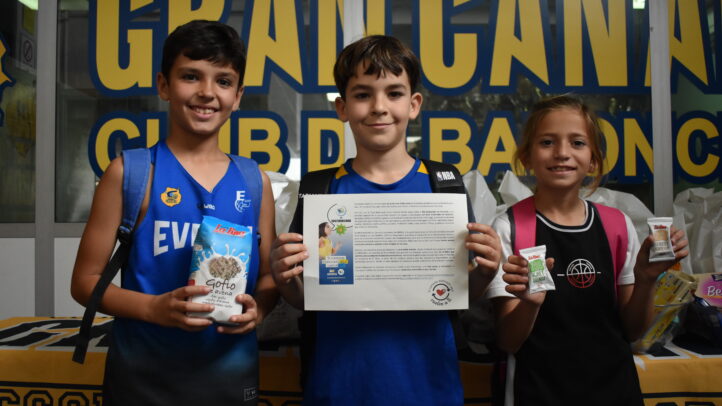 Niños sosteniendo productos locales y un documento en el X Clinic del Club Baloncesto Gran Canaria.