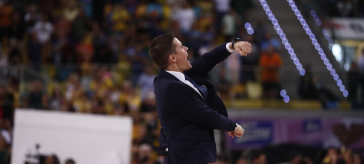 Entrenador celebrando con gesto de confianza ante una multitud en el estadio.
