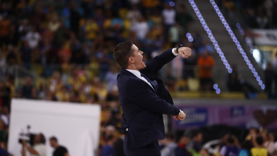 Entrenador celebrando con gesto de confianza ante una multitud en el estadio.