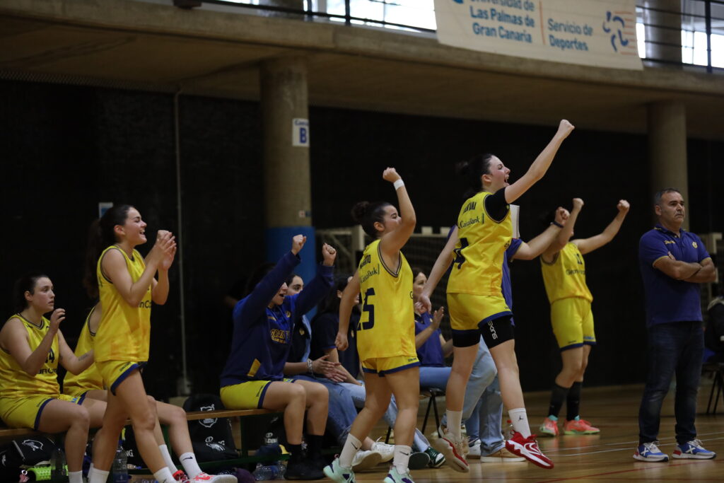 Jugadoras y entrenadores celebran en el banco durante un partido de baloncesto.