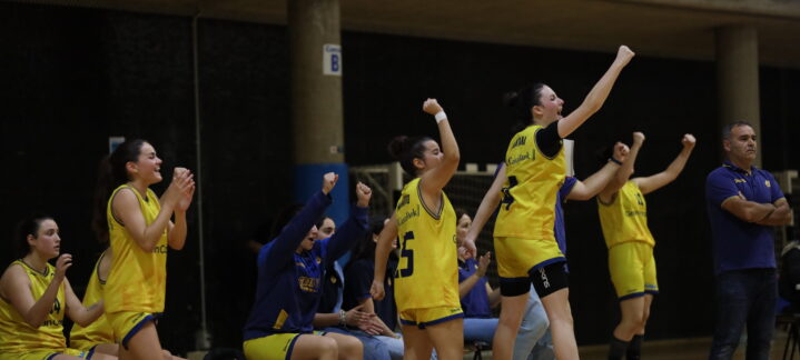 Jugadoras y entrenadores celebran en el banco durante un partido de baloncesto.