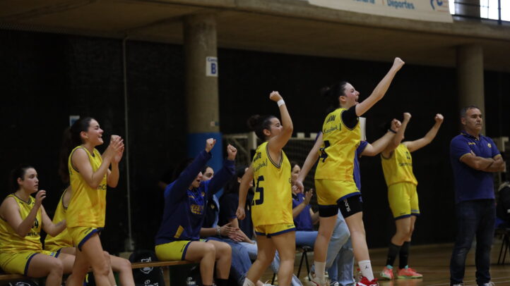 Jugadoras y entrenadores celebran en el banco durante un partido de baloncesto.