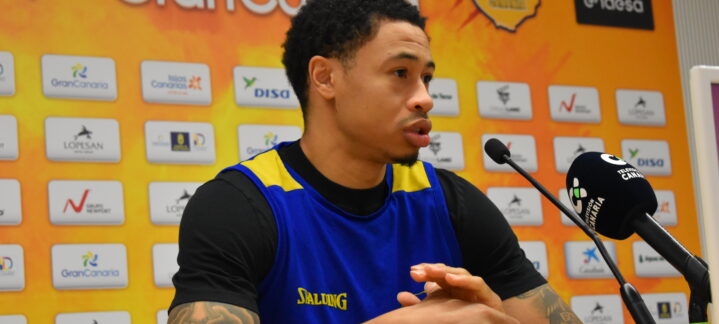 AJ Slaughter habla en rueda de prensa con el logo del equipo de fondo.