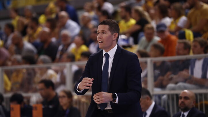 Entrenador Jaka Lakovic dirigiendo al equipo en una concurrida cancha de baloncesto.
