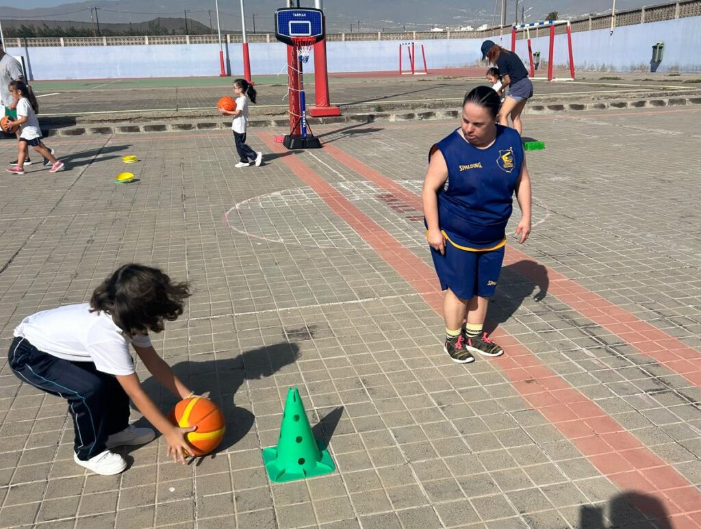 Niños jugando al baloncesto en una cancha, con porterías y conos de entrenamiento.