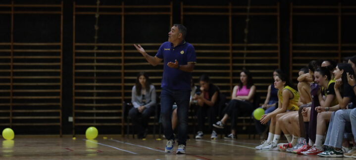 Entrenador dando instrucciones a jugadoras en el banquillo durante un partido.