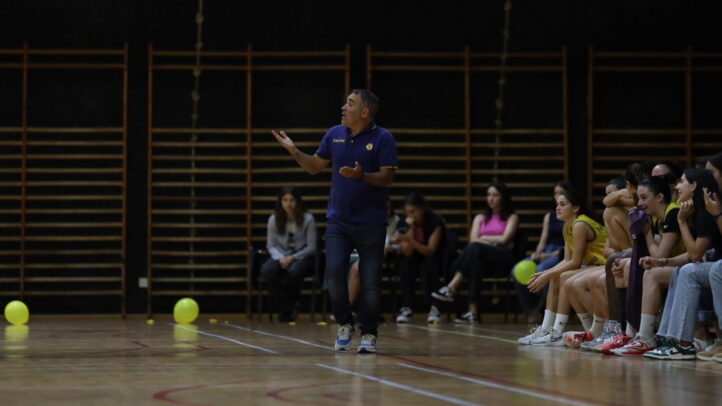Entrenador dando instrucciones a jugadoras en el banquillo durante un partido.
