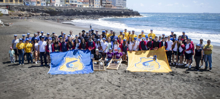 con su iniciativa 'Compromiso Granca', limpia la playa de La Garita","Grupo grande de personas en la playa de La Garita, con banderas del CB Gran Canaria.