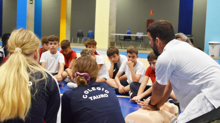 Grupo de jóvenes atentos a una demostración de primeros auxilios durante un entrenamiento.