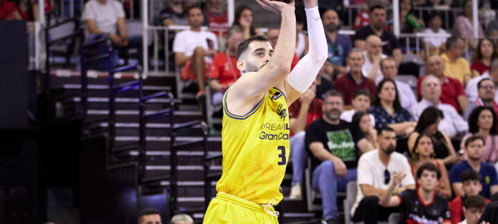 Jugador del CB Gran Canaria lanzando a canasta durante un partido, con público en las gradas.
