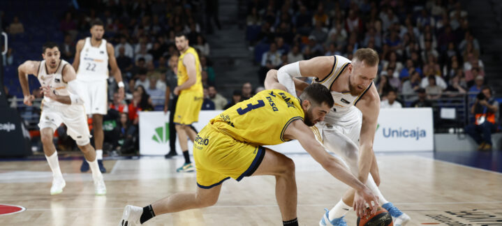 Juego intenso entre dos equipos de baloncesto, ambos luchando por el balón.