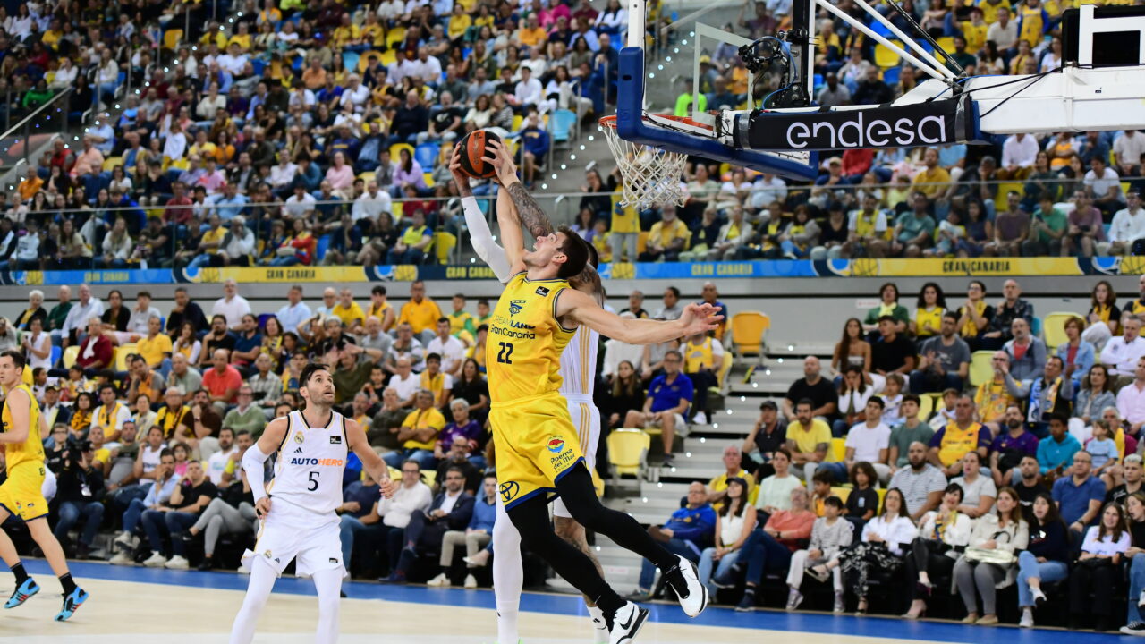 Jugador en acción realizando un mate durante un vibrante partido de baloncesto.