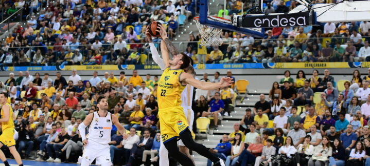 Jugador en acción realizando un mate durante un vibrante partido de baloncesto.