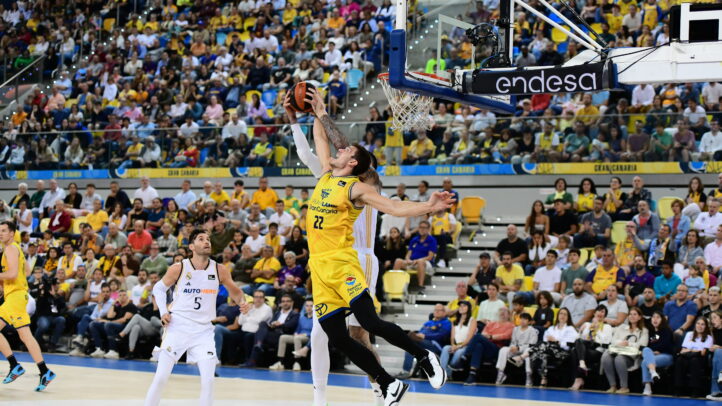 Jugador en acción realizando un mate durante un vibrante partido de baloncesto.