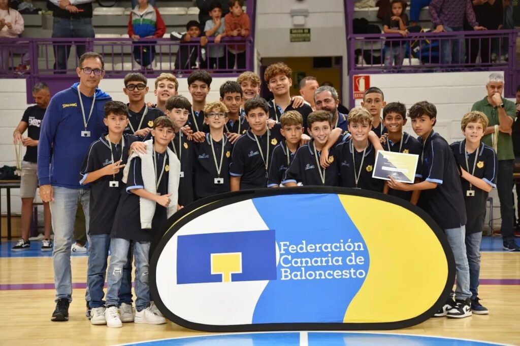 Grupo de jugadores preinfantiles y entrenador con medallas y un premio.