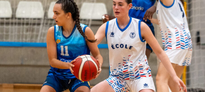 Jugadoras de baloncesto en acción, una con el balón y la otra defendiendo.
