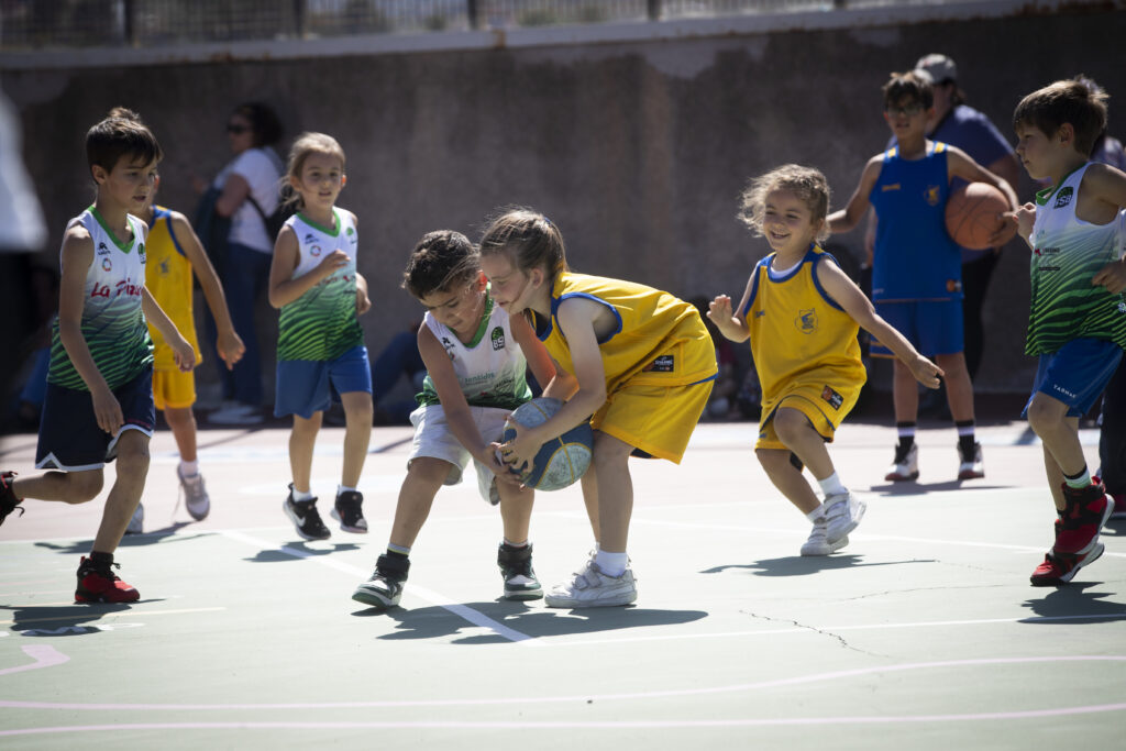 Niños jugando baloncesto en una cancha durante la última jornada de la Liga de Escuelas.