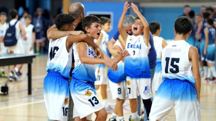 Jugadores de minibasket celebrando juntos tras un partido en el gimnasio.