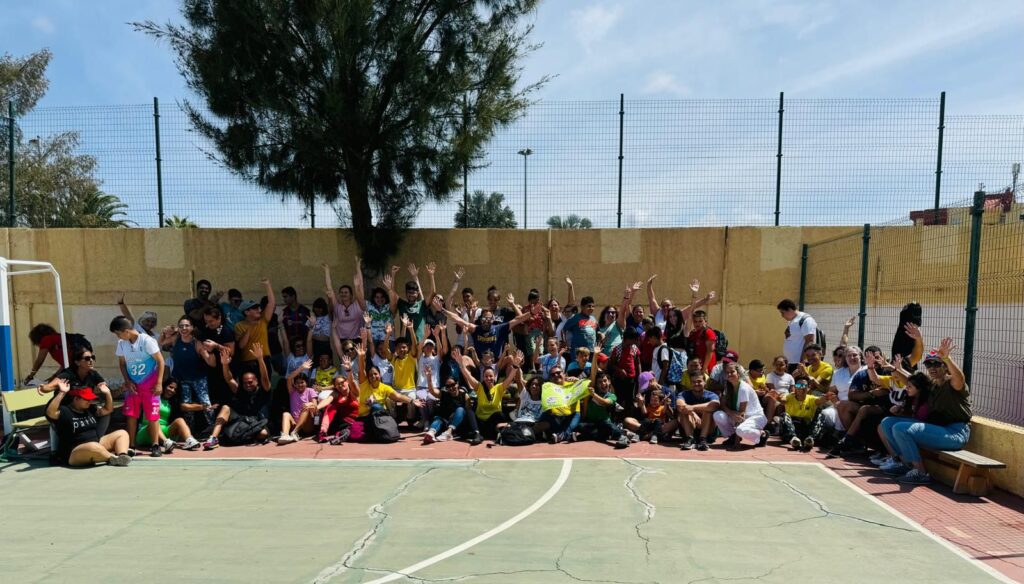 Gran grupo sonriente en un polideportivo, participando en un evento comunitario.
