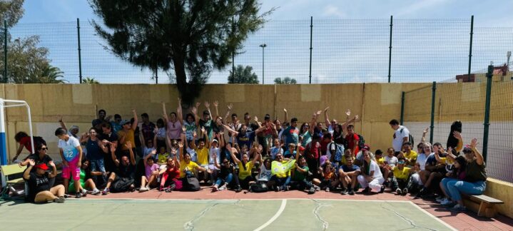 Gran grupo sonriente en un polideportivo, participando en un evento comunitario.