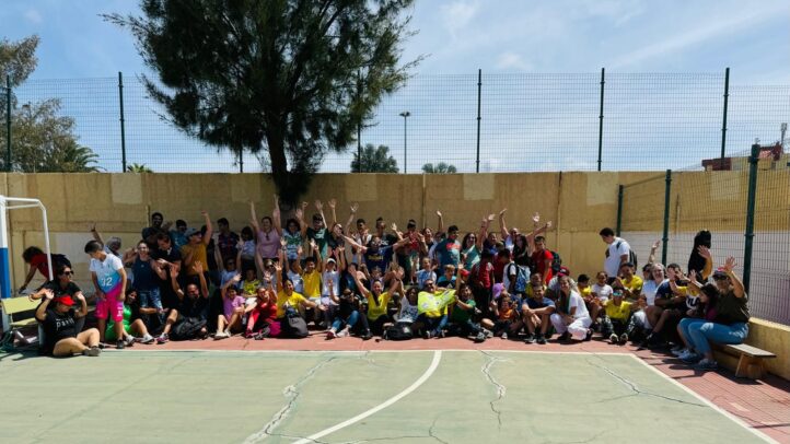 Gran grupo sonriente en un polideportivo, participando en un evento comunitario.