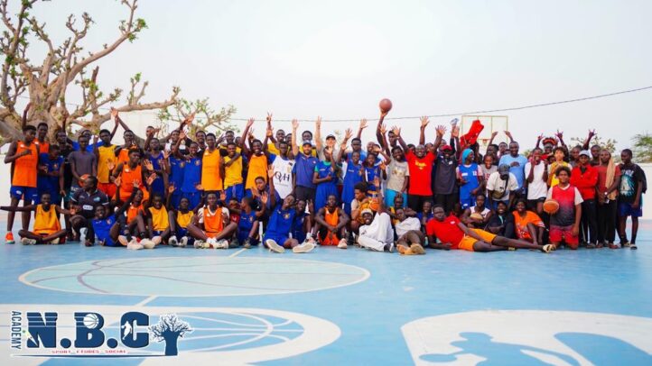Grupo diverso de jugadores y entrenadores de baloncesto posando en una cancha al aire libre.