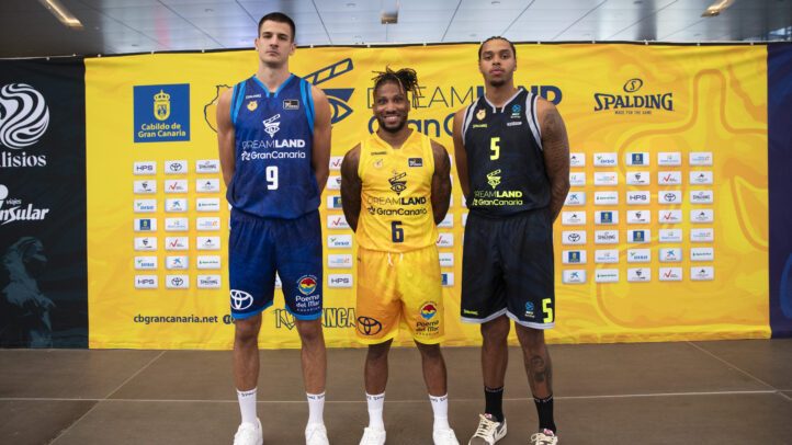 Tres jugadores del Dreamland Gran Canaria posan con diferentes uniformes, frente a un fondo colorido.