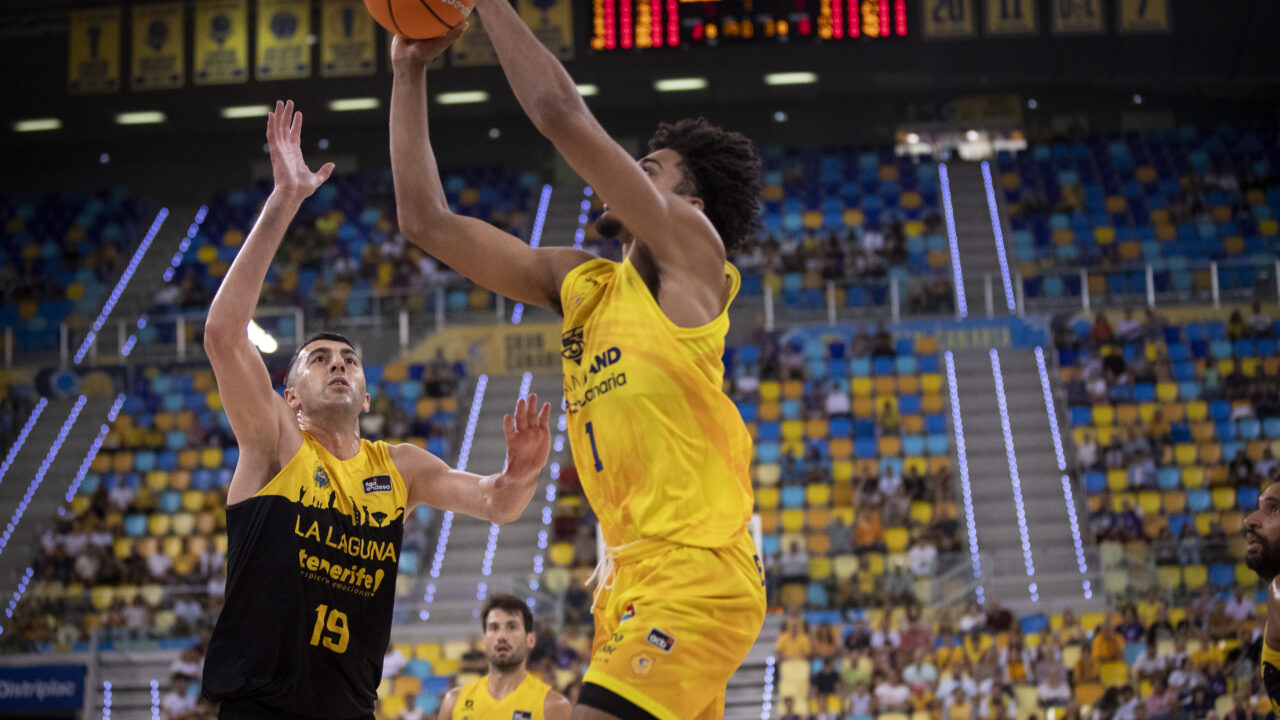 Jugador del Dreamland Gran Canaria lanza a canasta mientras es defendido por un oponente.