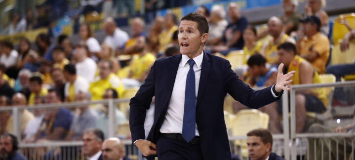 por eso estamos contentos por la victoria""","Entrenador Jaka Lakovic dirigiendo al equipo durante un partido, con público en las gradas.