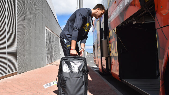 Jugador con mochila preparando el equipaje para abordar el autobús del equipo.