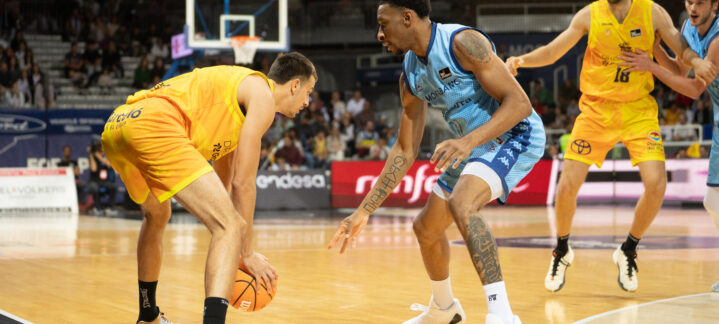 Dos jugadores de baloncesto compiten por el balón en una cancha.