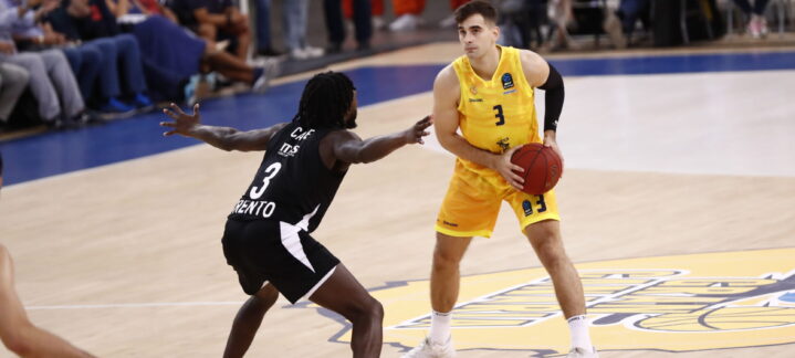 Dos jugadores de baloncesto en acción durante un partido, uno con balón en la mano.
