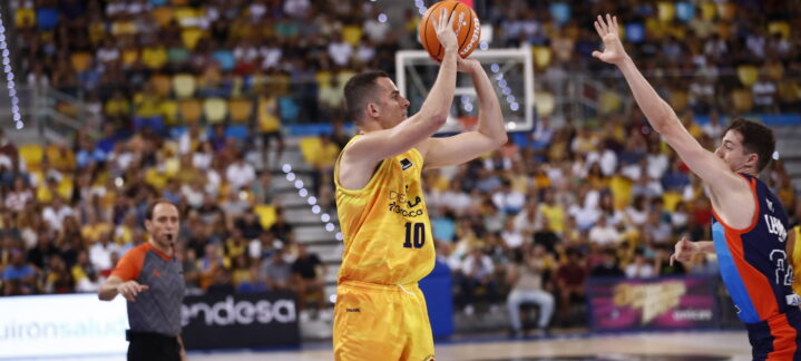 es una pista muy difícil""",Jugador de baloncesto lanzando a canasta con un árbitro y un rival cerca.