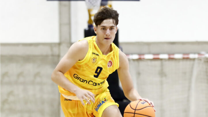 Jugando al baloncesto, un jugador del Gran Canaria avanza con el balón en la mano.