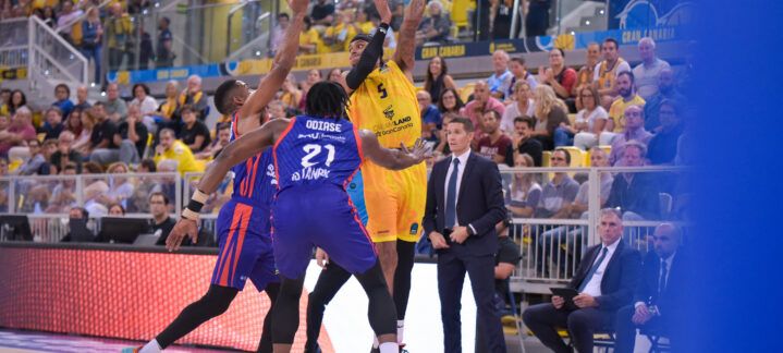 Jugador del Dreamland Gran Canaria lanza a canasta mientras es defendido por adversarios.