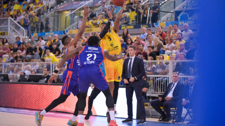 Jugador del Dreamland Gran Canaria lanza a canasta mientras es defendido por adversarios.
