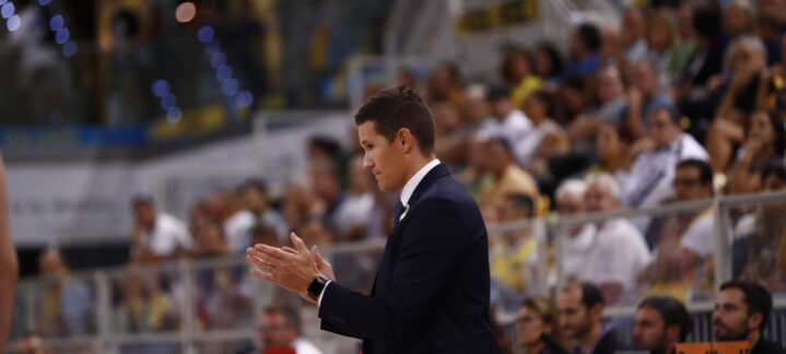 y por eso estoy contento""","Entrenador aplaudiendo durante un partido, con público al fondo.