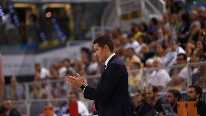 y por eso estoy contento""","Entrenador aplaudiendo durante un partido, con público al fondo.