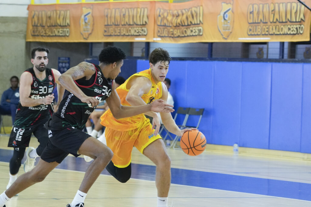Jugadores del Gran Canaria y Fibwi Palma compiten por el balón en una cancha de baloncesto.