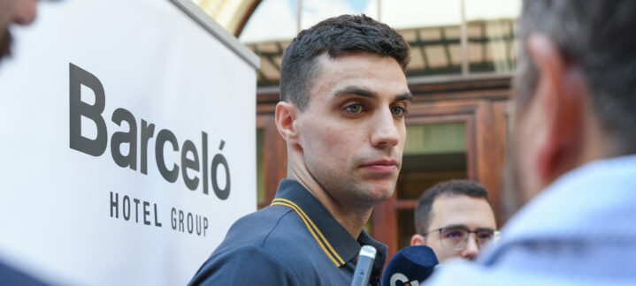 Carlos Alocén hablando con la prensa frente a un cartel de Barceló Hotel Group.