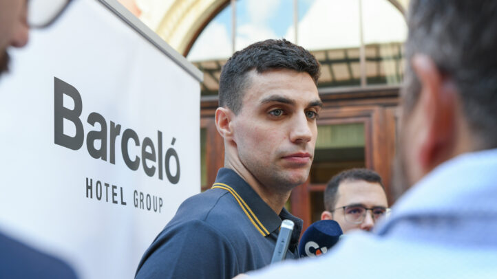 Carlos Alocén hablando con la prensa frente a un cartel de Barceló Hotel Group.