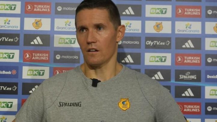decisión y unidad como equipo""","Entrenador Lakovic ofrece declaraciones antes de un partido, con fondo de patrocinadores.