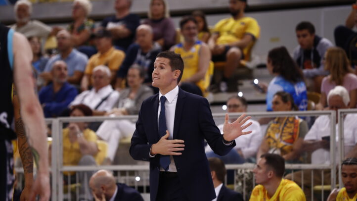 Entrenador en acción durante un partido, gesticulando y hablando con intensidad.