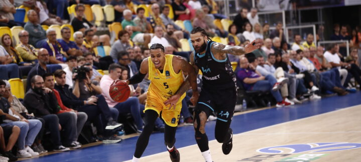 Jugador del Gran Canaria driblando mientras es seguido por un oponente en un partido.