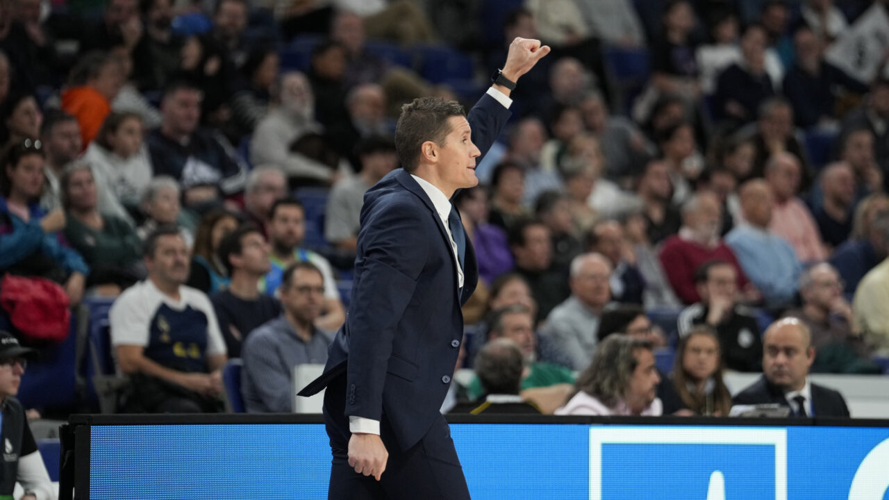 Entrenador gesticulando con entusiasmo durante un partido de baloncesto.
